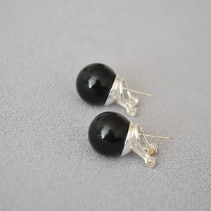 Macro shot of minimalist stud earrings featuring black agate beads with silver posts