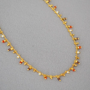 Detail of gold chain necklace featuring colorful mini beads and bohemian style accents