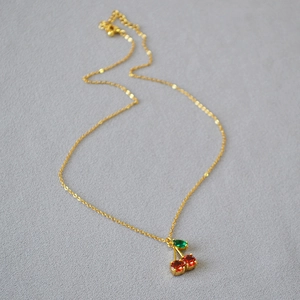 Collier élégant en laiton doré avec pendentif cerise rouge et petite feuille verte