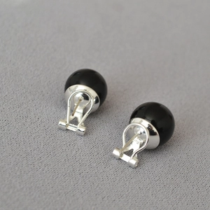 Close-up of black onyx stud earrings with S925 silver omega back clips on grey fabric