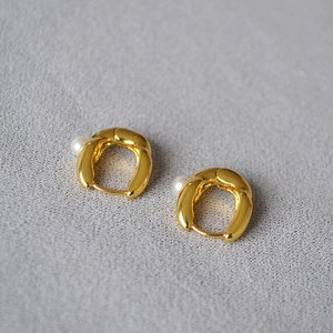 Minimalist gold-plated irregular U-shape earrings with small pearl accents on grey fabric
