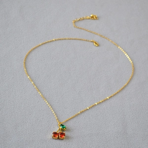 Collier minimaliste plaqué or avec pendentif cerise rouge et feuille en gemme verte