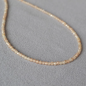 Gros plan d'un collier de perles fines facettées orange champagne sur tissu foncé