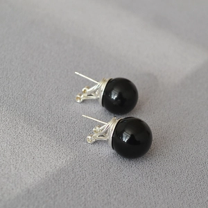 Minimalist 925 silver stud earrings featuring large black onyx round beads on grey texture