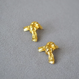 Vue macro de boucles d'oreilles nœud dorées avec texture de lave fondue irrégulière