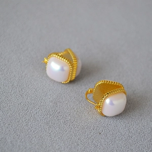 Vue macro des boucles d'oreilles en laiton doré avec perle Mabe et bordure perlée