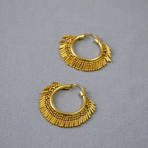 Detail view of gold hoop earrings with dense metal fringe tassels in tribal style