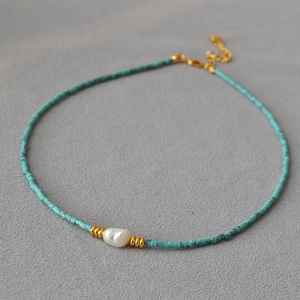 Detail of turquoise beaded necklace with baroque pearl and golden lobster clasp closure