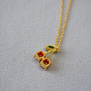 Collier minimaliste plaqué or avec pendentif cerise rouge doux et détail de feuille verte