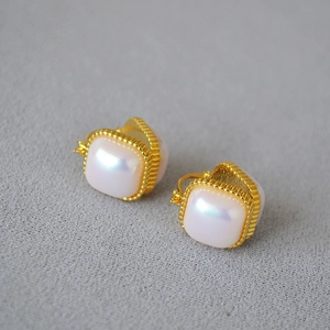 Vue détaillée de boucles d'oreilles carrées en perle Mabe avec bordure dorée perlée