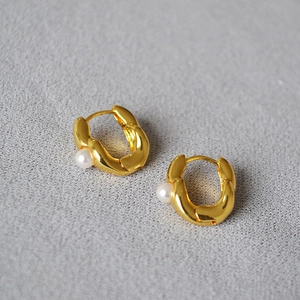 Macro detail of irregular U-shaped gold brass earrings with small white pearls