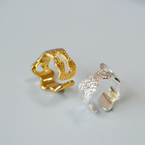 Detailed view of adjustable gold and silver rings with irregular lava texture and cutout design