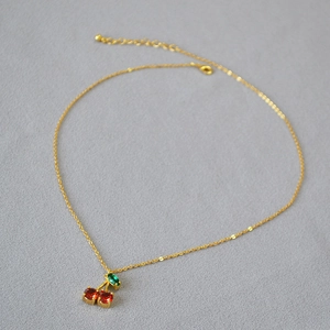 Détail du collier cerise avec pendentifs en cristal rouge et vert sur chaîne dorée