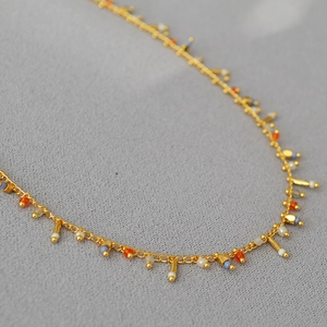 Detailed view of bohemian gold chain necklace with colorful beads and small bars