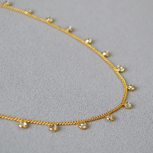 Detailed close-up of gold-plated choker with multiple sparkling bezel-set crystals