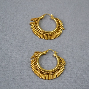Detail of gold-plated hoop earrings featuring vintage dangling beaded metal tassels