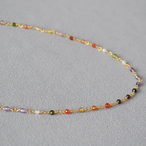 Macro view of dainty gold chain with multi-color faceted zircon beads and wire-wrap detail
