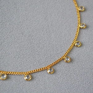 Detail of gold-plated brass necklace featuring bezel-set round crystal pendants