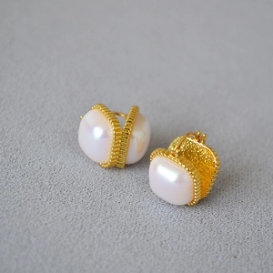 Vue détaillée de boucles d'oreilles en laiton doré avec perle Mabe et cadre texturé vertical