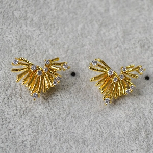 Dettaglio dei orecchini a cuore dorati con cristalli e design radiale scintillante