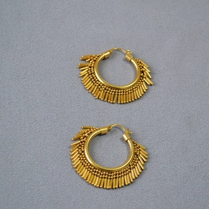 Detail of gold-plated brass hoop earrings with bohemian tassel-style metal fringe texture