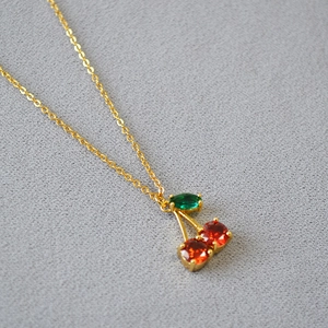 Gros plan d'un collier pendentif cerise avec pierres précieuses rouges et vertes