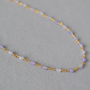 Elegant gold-plated brass necklace with handmade lavender stone beads on a textured surface