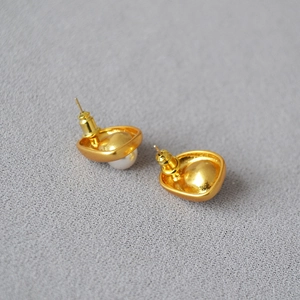 Detailed macro view of baroque gold-plated brass stud earrings with lustrous pearls