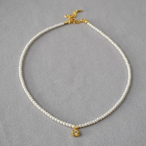 Collier de perles élégant avec pendentif fleur en or et zircon sur fond gris texturé