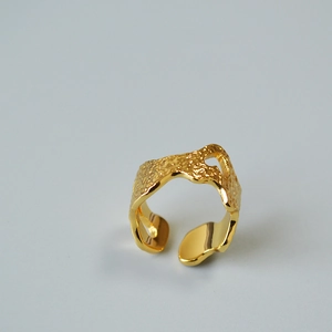Macro shot of gold-plated brass ring with irregular lava texture and open-loop design