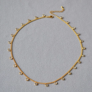 Detail of gold-plated choker necklace featuring evenly spaced clear crystal charms