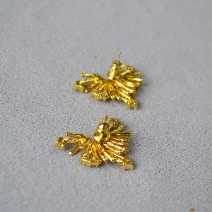 Dettaglio macro di orecchini a ventaglio placcati oro con zirconi cubici scintillanti
