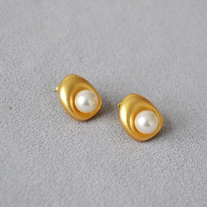Macro detail of French vintage baroque stud earrings with matte gold finish and white pearls