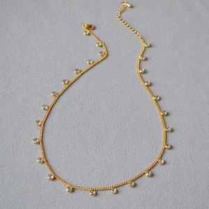 Detail of gold-plated brass necklace featuring crystal zircon drops and a lobster clasp