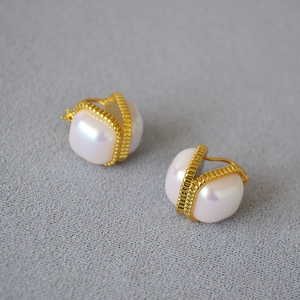 Gros plan détaillé de boucles d'oreilles perles Mabe avec monture dorée texturée