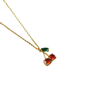 Collier minimaliste en laiton plaqué or avec pendentif cerise rouge sur fond blanc pur