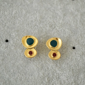 Close-up of irregular gold earrings with vintage emerald green and burgundy enamel details