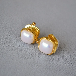Vue détaillée de boucles d'oreilles carrées en perle mabe avec bordure perlée dorée
