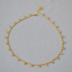Detail of gold-plated choker necklace featuring sparkling cubic zirconia charms and lobster clasp