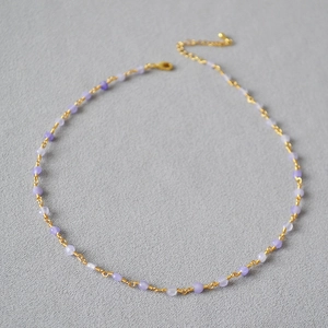 Detail of beaded gold chain necklace featuring lavender stones and lobster clasp closure
