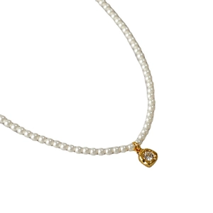 Collier de perles élégant avec pendentif fleur en zircon doré sur un fond blanc pur