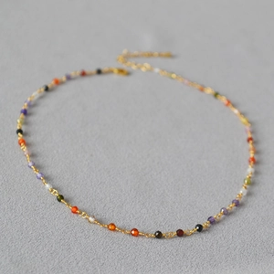 Macro detail of colorful faceted beads and gold-plated chain with lobster clasp