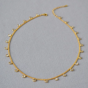 Detailed view of a gold-plated necklace featuring sparkling zircon crystals and lobster clasp