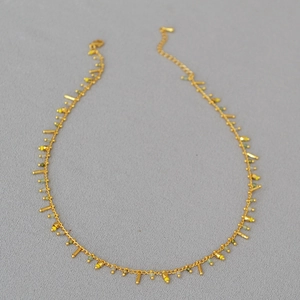 Detail of gold beaded necklace with yellow and green beads and lobster clasp closure