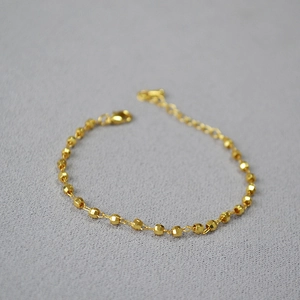 Close-up of faceted gold-plated beads bracelet with lobster clasp and adjustable tail chain