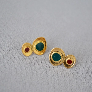 Macro view of vintage irregular geometric earrings with green and red enamel on gold metal