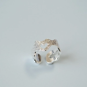 Macro view of adjustable silver ring with hammered texture and hollow heart design