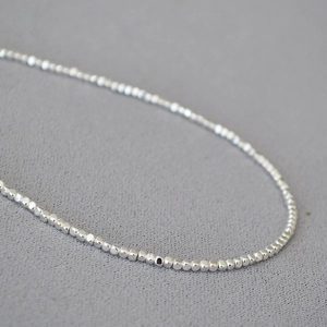 Vue macro d'une chaîne minimaliste à billes d'argent facettées avec finition polie