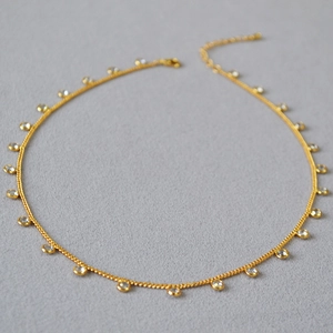 Detail view of a gold plated necklace featuring round cubic zirconia in bezel settings