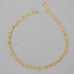 Detail view of dainty gold beaded necklace with colorful beads and metal pendants